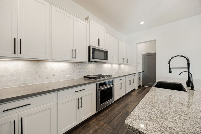 kitchen featuring white cabinetry, sink, dark wood-type flooring, light stone counters, and appliances with stainless steel finishes