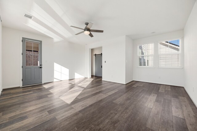 unfurnished room featuring a barn door, dark hardwood / wood-style floors, and ceiling fan