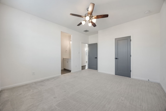 unfurnished bedroom featuring ceiling fan, light colored carpet, and connected bathroom