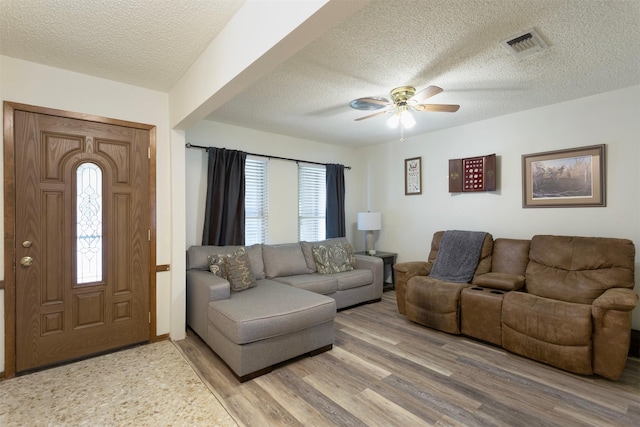 living room with ceiling fan, plenty of natural light, wood-type flooring, and a textured ceiling