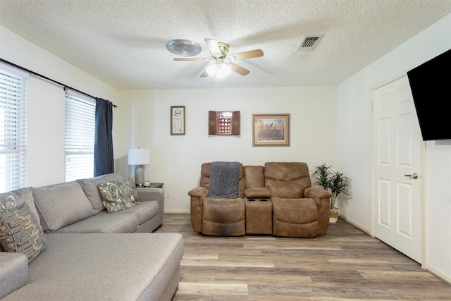 living room featuring a textured ceiling, light hardwood / wood-style floors, and ceiling fan