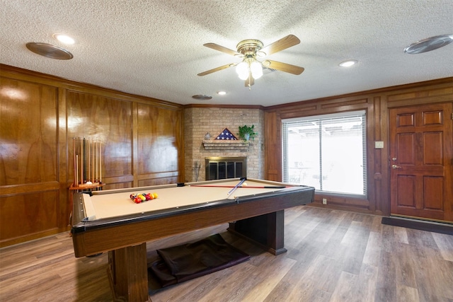 playroom with hardwood / wood-style flooring, a brick fireplace, crown molding, and pool table