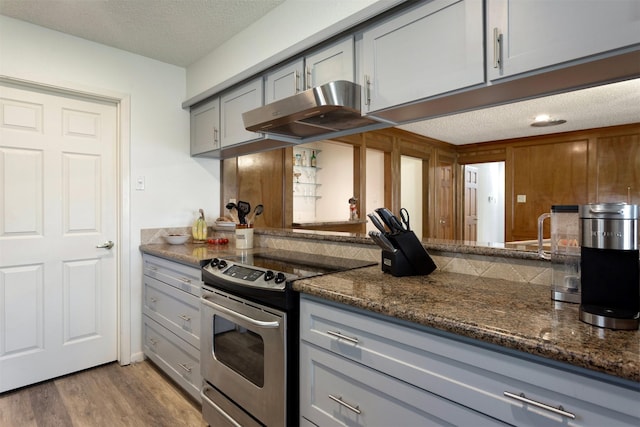 kitchen featuring dark stone counters, gray cabinets, stainless steel electric range oven, a textured ceiling, and light hardwood / wood-style floors