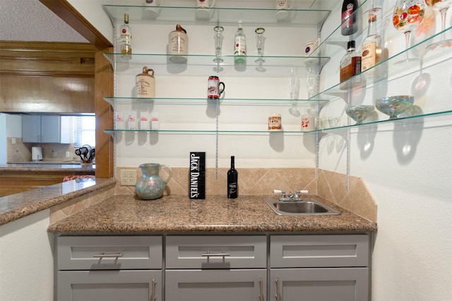 kitchen featuring stone countertops, gray cabinets, and sink