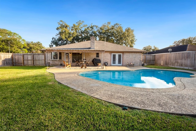 view of pool with french doors, a patio, and a lawn