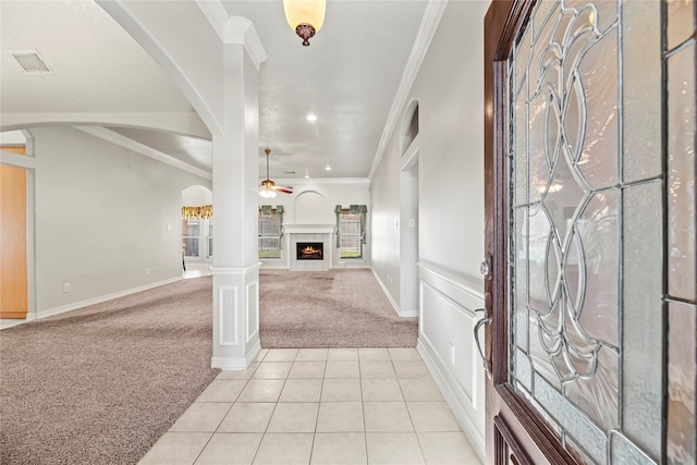 entryway featuring light carpet, decorative columns, ceiling fan, and ornamental molding