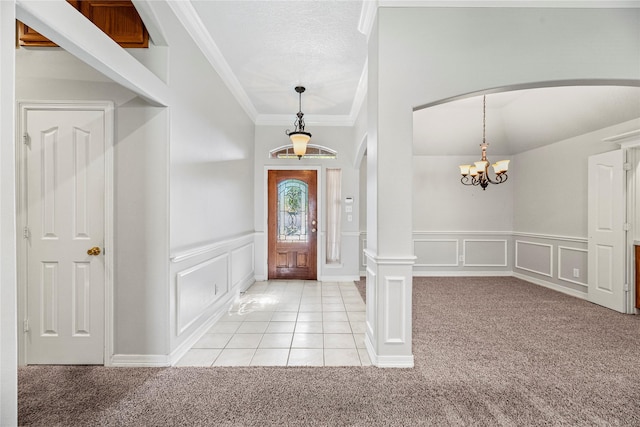 carpeted entrance foyer featuring ornamental molding and a chandelier