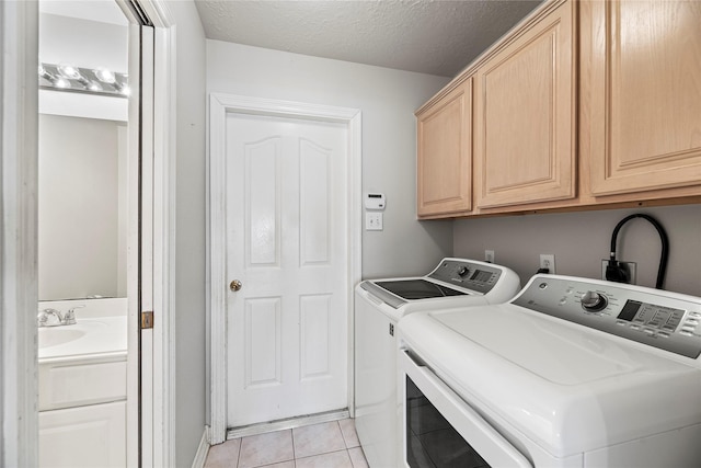 clothes washing area with cabinets, a textured ceiling, sink, washing machine and dryer, and light tile patterned flooring