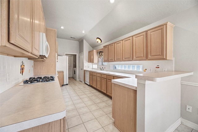 kitchen with kitchen peninsula, white appliances, lofted ceiling, decorative backsplash, and light tile patterned floors