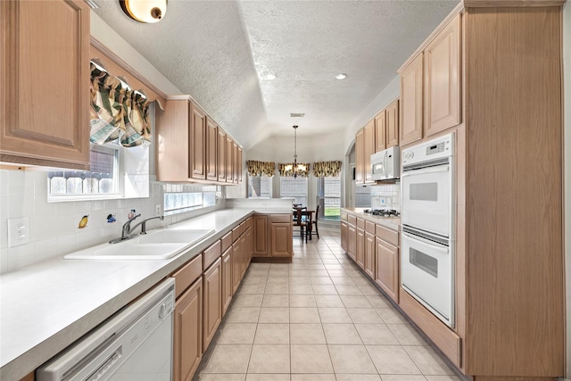 kitchen with white appliances, decorative light fixtures, a wealth of natural light, and sink