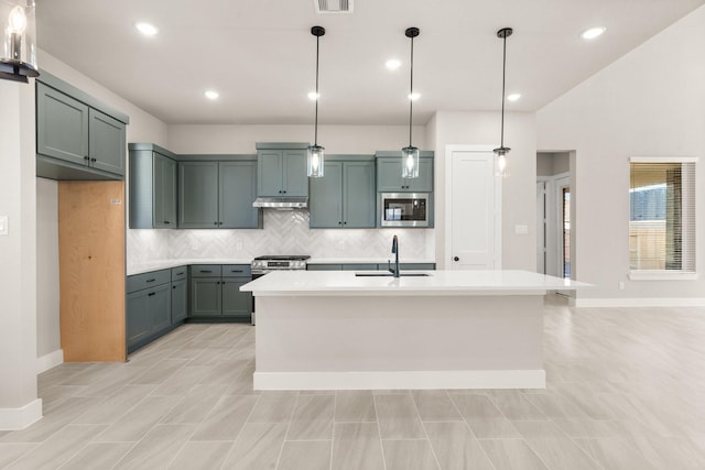 kitchen with sink, stainless steel appliances, hanging light fixtures, and a center island with sink