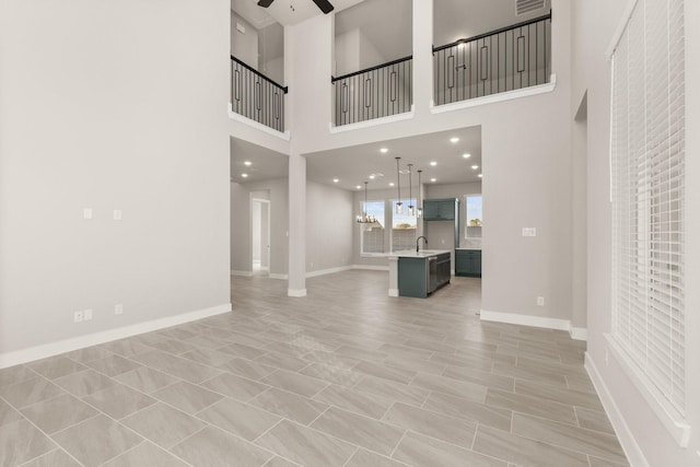 unfurnished living room with sink, ceiling fan, and a high ceiling