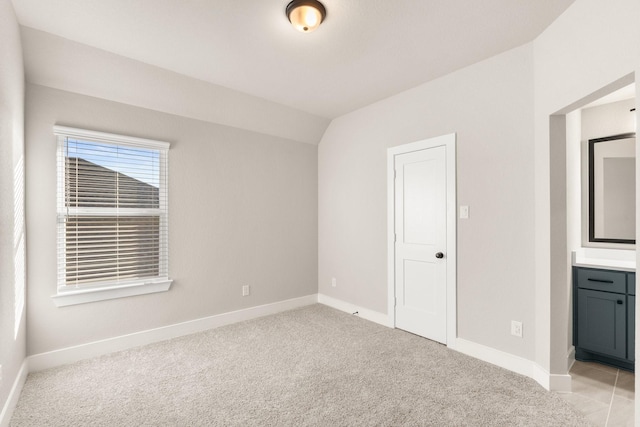 unfurnished bedroom with light colored carpet, lofted ceiling, and a closet