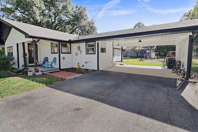 ranch-style home with a front lawn, covered porch, and a carport