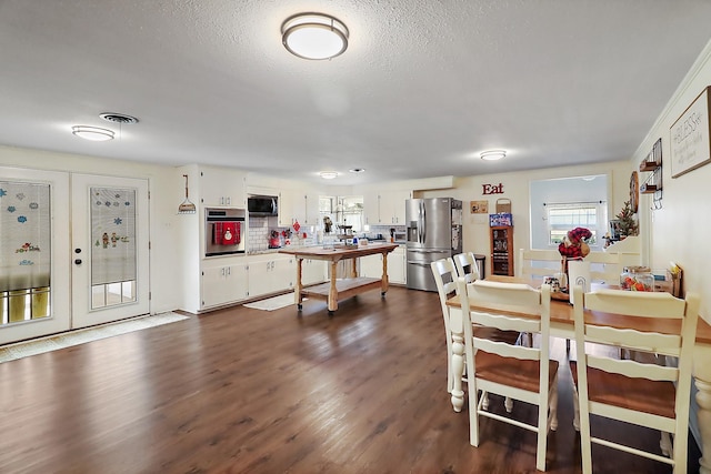 dining space featuring a textured ceiling, dark wood-type flooring, and french doors