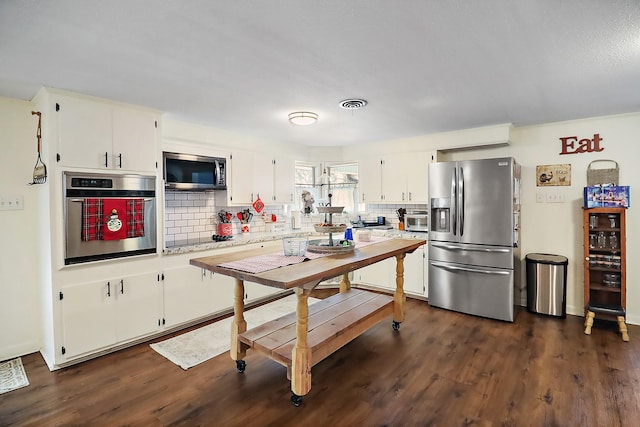 kitchen featuring decorative backsplash, appliances with stainless steel finishes, and white cabinetry