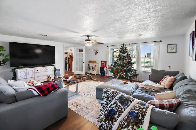 living room with a textured ceiling, dark hardwood / wood-style flooring, and ceiling fan