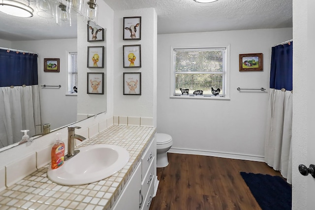 bathroom with vanity, wood-type flooring, a textured ceiling, and toilet