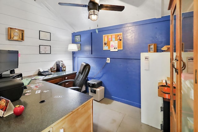 office featuring ceiling fan, lofted ceiling, and wood walls