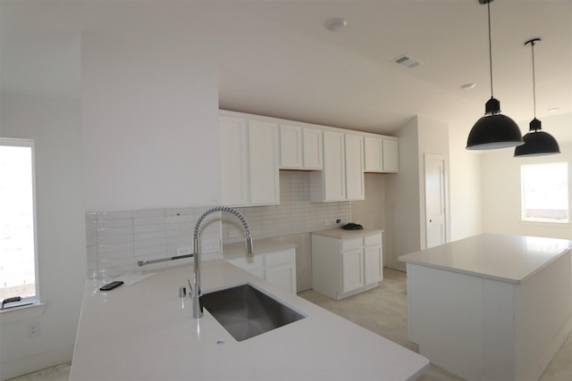 kitchen featuring a sink, backsplash, a kitchen island, and white cabinets