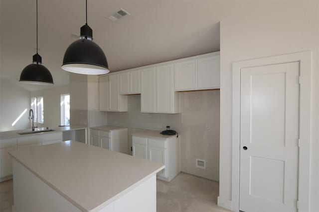 kitchen with visible vents, backsplash, a center island, white cabinets, and a sink