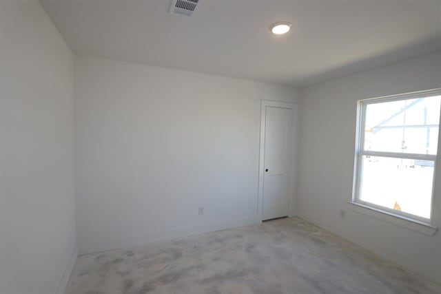 unfurnished room with unfinished concrete floors, baseboards, visible vents, and a wealth of natural light