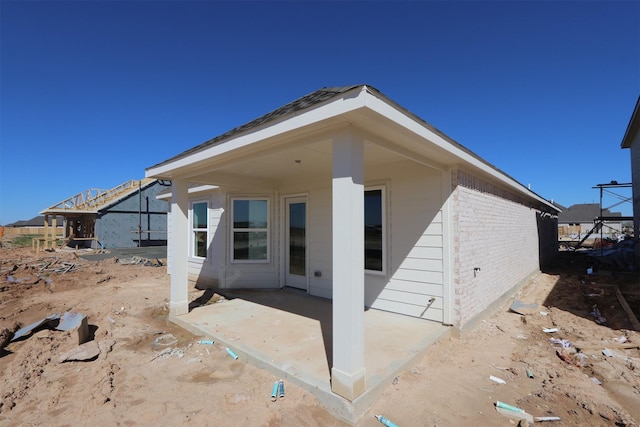 rear view of property with brick siding and a patio