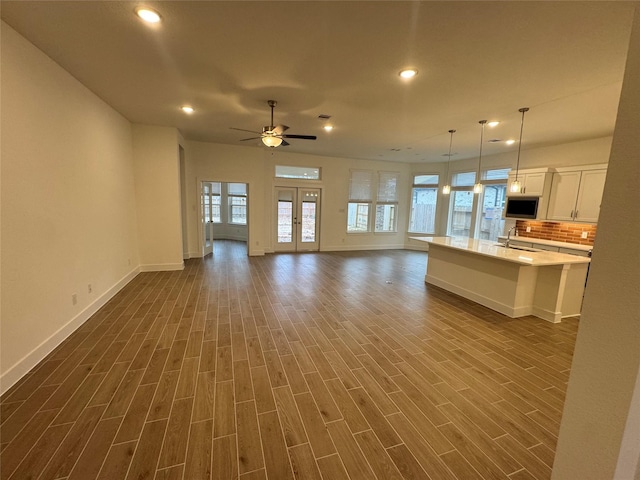 unfurnished living room with ceiling fan, dark hardwood / wood-style flooring, and sink