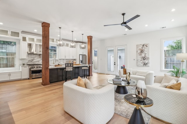 living room featuring decorative columns, light hardwood / wood-style flooring, ceiling fan, and sink