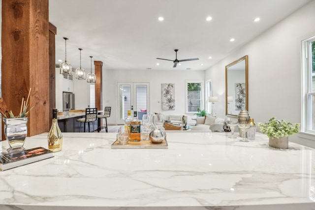 kitchen featuring light stone counters, a healthy amount of sunlight, and decorative light fixtures