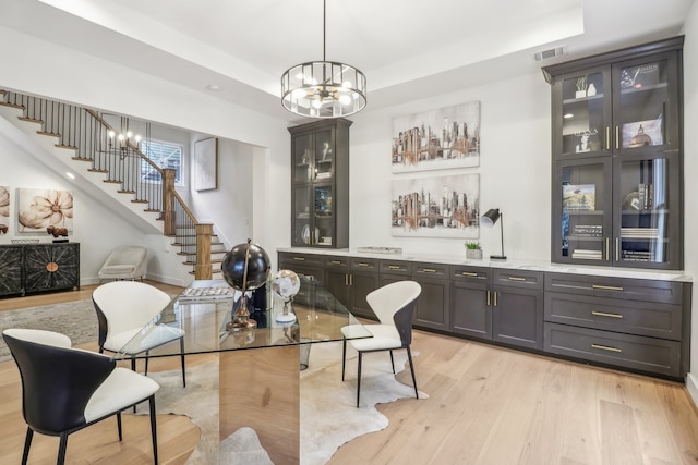 dining area featuring indoor bar, light hardwood / wood-style floors, and an inviting chandelier