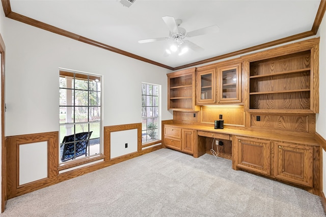 office space with ceiling fan, light colored carpet, built in desk, and ornamental molding