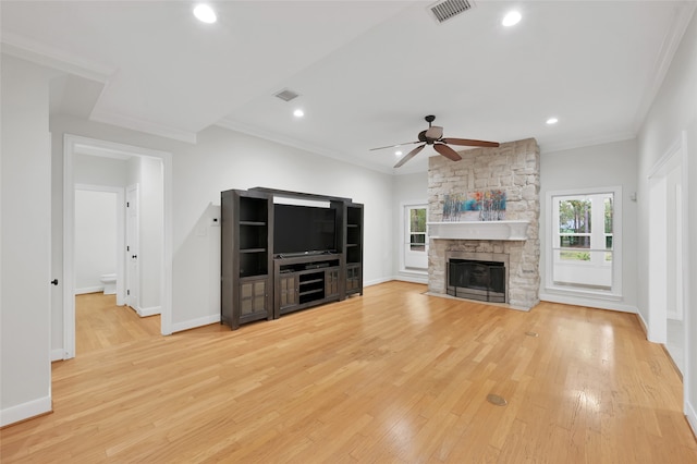 unfurnished living room featuring light hardwood / wood-style floors, a stone fireplace, ceiling fan, and crown molding