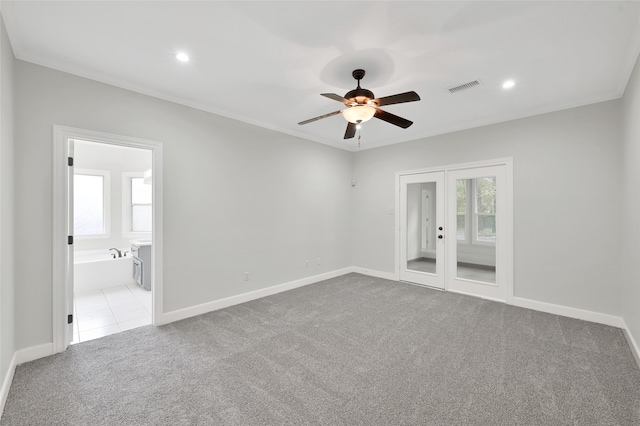 empty room featuring crown molding, ceiling fan, french doors, and light colored carpet