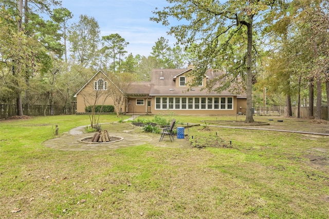 back of house featuring a fire pit, a sunroom, and a lawn