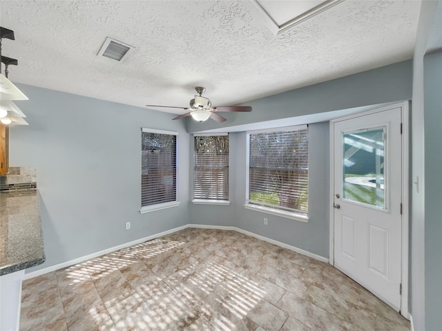 unfurnished dining area with light tile patterned floors, a textured ceiling, and ceiling fan