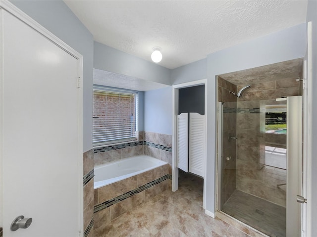 bathroom featuring a textured ceiling and separate shower and tub