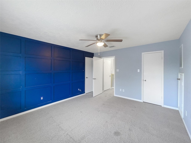 unfurnished bedroom with a textured ceiling, ceiling fan, and light carpet