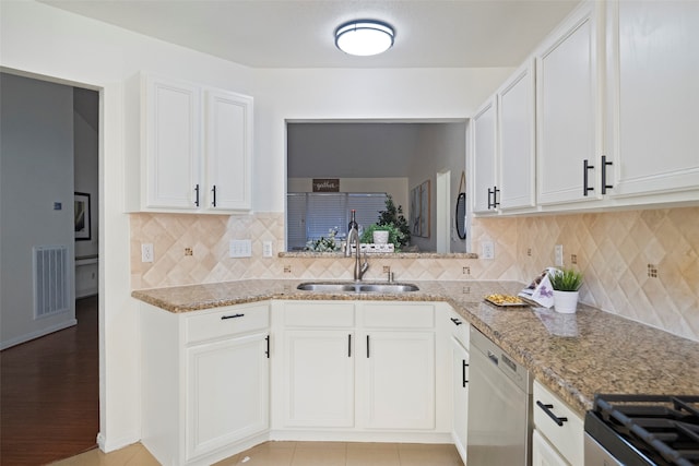 kitchen featuring stainless steel dishwasher, white cabinetry, sink, and tasteful backsplash