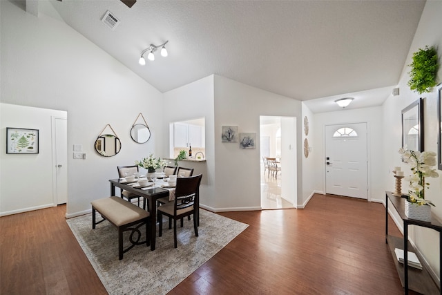 dining space with a textured ceiling, dark hardwood / wood-style flooring, and vaulted ceiling