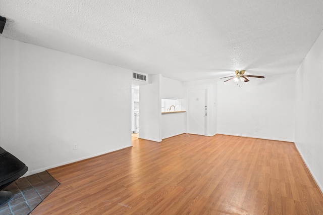 unfurnished living room featuring ceiling fan, light hardwood / wood-style floors, and a textured ceiling