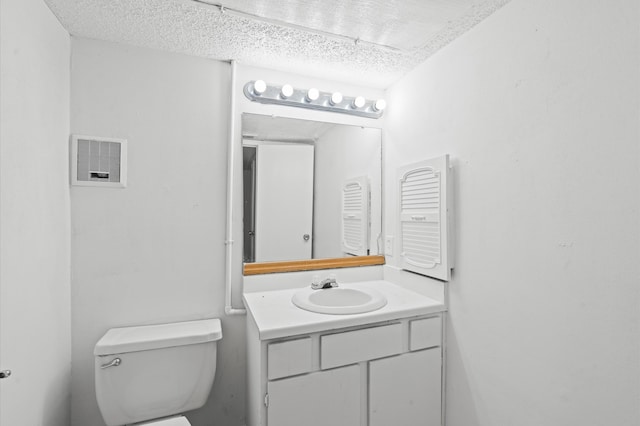 bathroom featuring a textured ceiling, vanity, and toilet