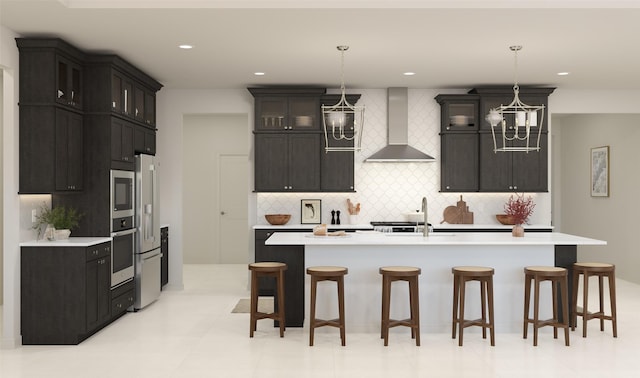 kitchen with backsplash, a center island with sink, hanging light fixtures, and wall chimney exhaust hood