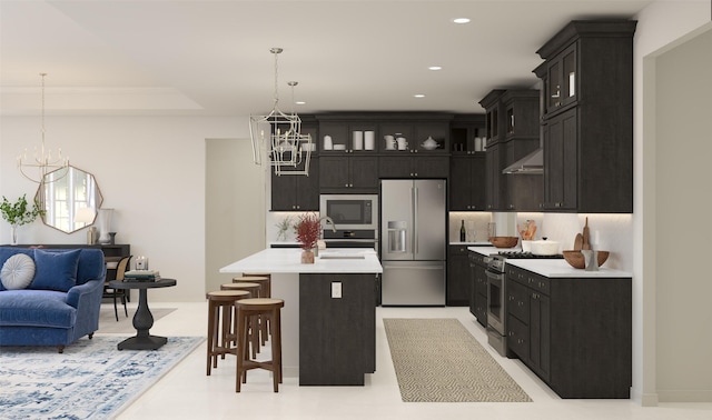 kitchen with stainless steel appliances, an inviting chandelier, an island with sink, decorative light fixtures, and a breakfast bar