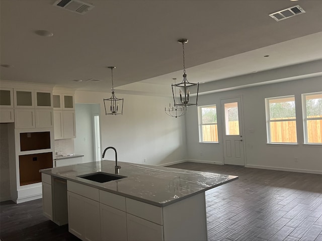 kitchen with white cabinetry, a center island with sink, light stone countertops, and sink