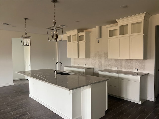 kitchen featuring dark stone counters, a large island, sink, and dark wood-type flooring