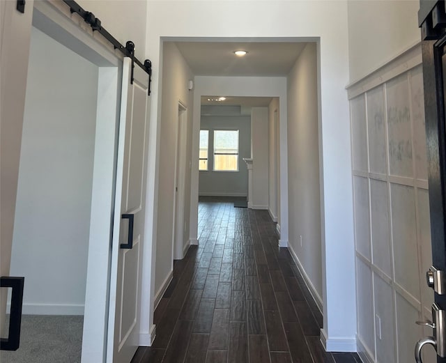 hall featuring dark wood-type flooring and a barn door