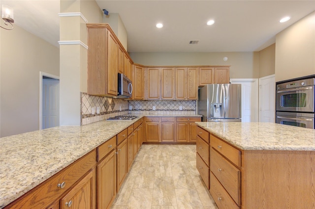 kitchen with decorative backsplash, light stone counters, a center island, and appliances with stainless steel finishes