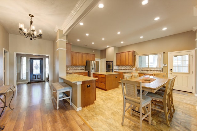 kitchen with kitchen peninsula, plenty of natural light, stainless steel appliances, and light wood-type flooring