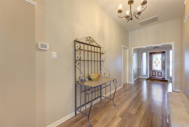 entryway featuring a notable chandelier, wood-type flooring, and high vaulted ceiling